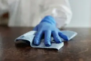 A hand wearing a blue glove wipes a surface with a cloth, emphasizing hygiene and cleanliness.